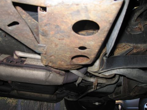 1991 Ford LTD Crown Victoria - The underside of a vehicle shows significant rust on the frame and exhaust components.