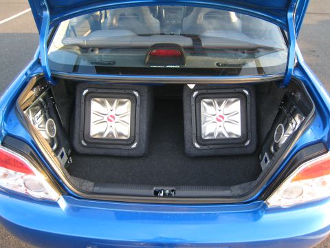 2007 Subaru Impreza - The trunk of a blue 2007 Subaru Impreza features two Kicker subwoofers and additional speakers mounted on the sides.