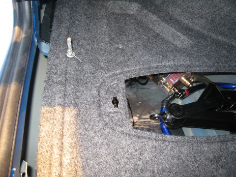 2007 Subaru Impreza - Trunk interior with audio components and jack visible through an opening in the carpet.