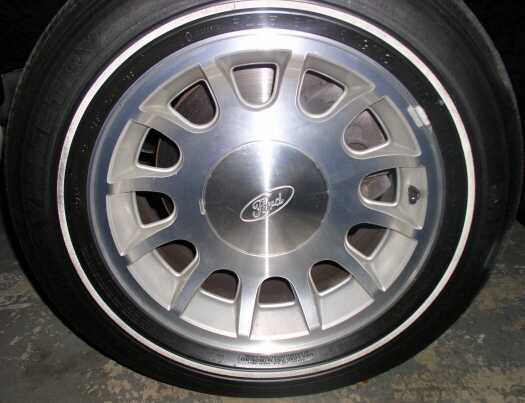 Close-up of a Ford wheel and tire. The wheel has a silver finish with a black stripe around the rim