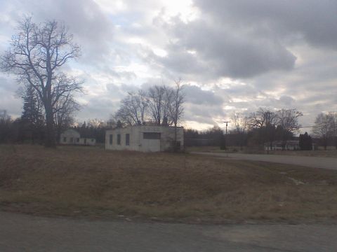2008 Mazda 3 - A cloudy sky looms over a rural landscape with several buildings and leafless trees.