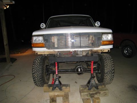 1996 Ford Bronco - Front view of a 1996 Ford Bronco, lifted on jack stands, revealing its modified suspension and undercarriage.