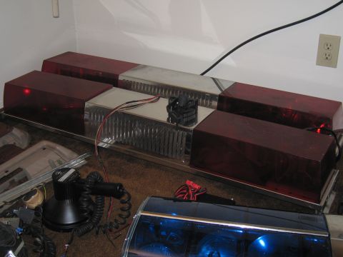 1991 Ford LTD Crown Victoria - A collection of emergency vehicle lights, including a red light bar and a spotlight, are shown indoors.