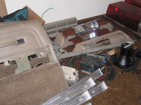 1991 Ford LTD Crown Victoria - Disassembled car interior components and emergency lighting are scattered on a brown carpeted surface.