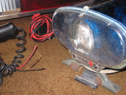 1991 Ford LTD Crown Victoria - A close-up of a vehicle spotlight and associated wiring, resting on a carpeted surface.