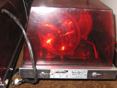1991 Ford LTD Crown Victoria - Close-up of a red Federal Twin Sonic emergency light, showing internal components and a product label.