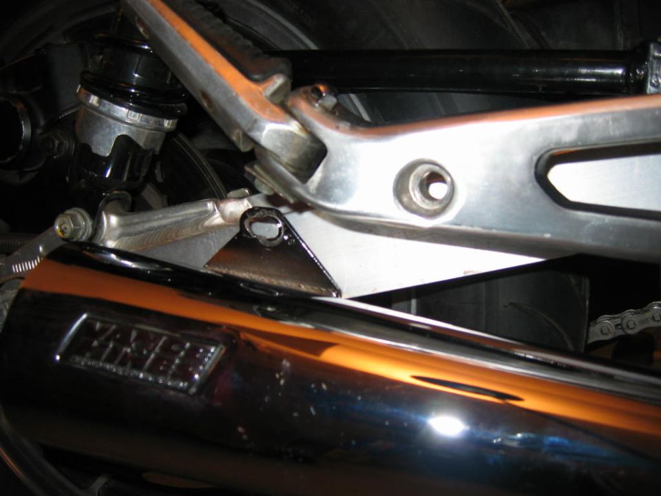 Close-up of a chrome motorcycle exhaust pipe with 'YAMAHA' logo, showing part of the rear suspension