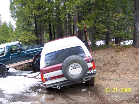 1991 Ford Bronco - Two Ford Broncos navigate a snowy, wooded trail on a winter day.