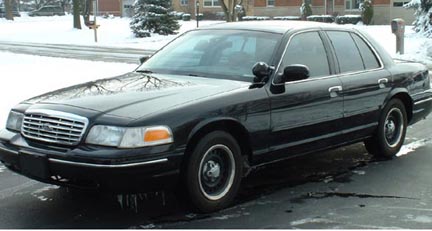 1998 Ford Crown Victoria - A black 1998 Ford Crown Victoria sedan is parked on a street covered in snow.