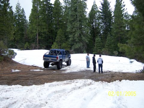 1991 Ford Bronco - Modified pickup truck in a snowy forest setting with three onlookers. Date stamp indicates 2005.