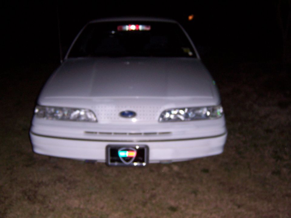 Front view of a white Ford sedan at night with Ford oval badge and front plate
