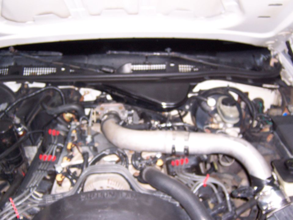 Under-hood view of a V8 engine with aluminum intake tube in a white 1992 Ford Crown Victoria