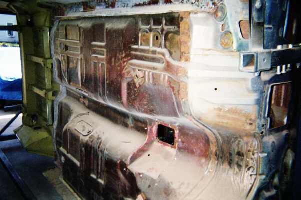 Bare metal firewall and floor of a vehicle body shell being restored