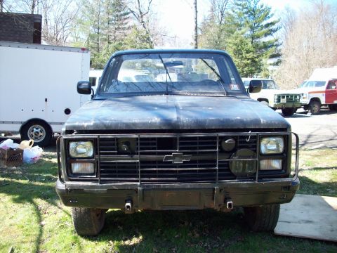 1987 Suzuki Samurai - Frontal view of a black Chevrolet pickup truck, likely from the 1980s, with a prominent brush guard.