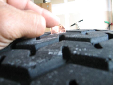 1993 Ford Bronco - A penny is used to gauge the tread depth of a tire.