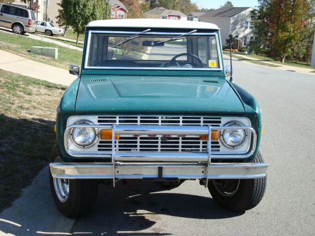 Green Ford Bronco with white top and chrome grille guard