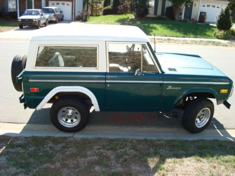 1977 Ford Bronco - A 1977 Ford Bronco in dark green with a white roof is parked on a residential street.