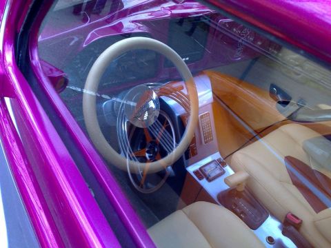 1991 Ford Crown Victoria - The interior of a customized car features tan leather seats and a unique steering wheel.