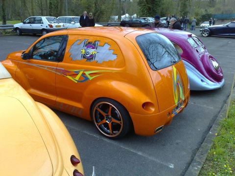 1991 Ford Crown Victoria - Customized PT Cruiser with graphics parked next to a classic car at an outdoor event.