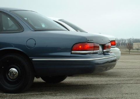 1998 Ford Crown Victoria - Rear view of a blue 1998 Ford Crown Victoria, showing its distinctive taillight and body style, with another vehicle visible behind.