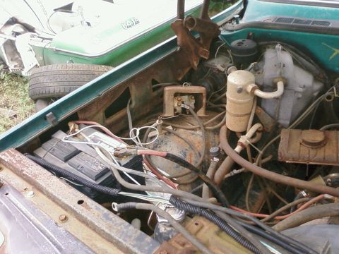 1979 Chevrolet Cheyenne - The engine bay of a green vehicle shows signs of rust and disrepair, with another vehicle partially visible in the background.