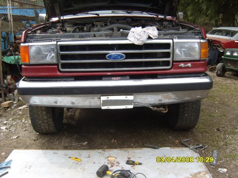 1989 Ford Bronco - Front view of a red Ford truck, possibly a Bronco, with its hood open and a 4x4 badge visible on the fender.
