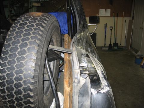 1989 Ford Bronco - Spare tire and damaged vehicle door in a garage setting.