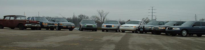 Front view of a line of police cars, including a 1998 Ford Crown Victoria