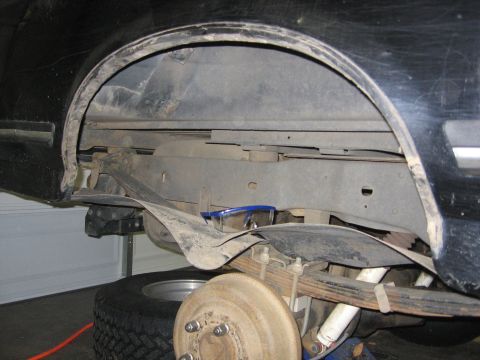 1989 Ford Bronco - Close-up view of the rear suspension and wheel well of a black vehicle.