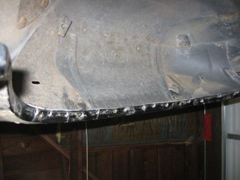 1989 Ford Bronco - Close-up of the underside of a bare-metal body panel showing a row of ground-down plug welds along its lower flange where a new skin was we…