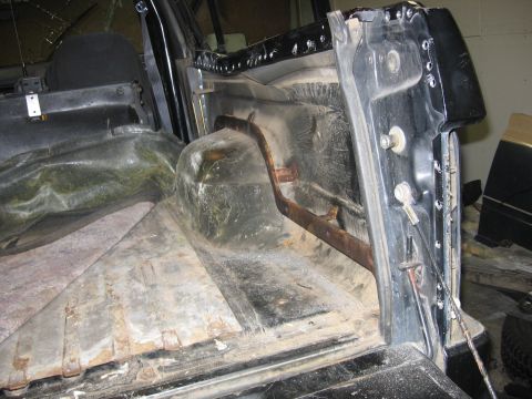1989 Ford Bronco - The interior of a vehicle's cargo area is shown, with visible wear and tear on the floor and wheel wells.