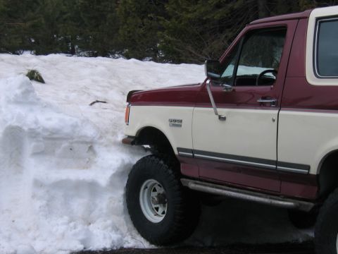 1991 Ford Bronco - A two-tone 1991 Ford Bronco navigates a snowy path.