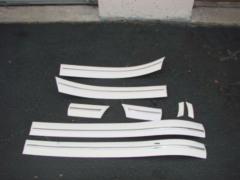 1997 Mercury Grand Marquis - Several white body side moldings with chrome trim are laid out on a dark surface.