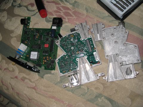 2007 Subaru Impreza - Close-up of disassembled electronic components, including circuit boards and metal housing, laid out on a textured surface.