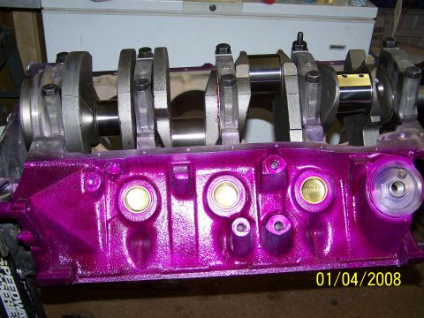 1995 Ford Bronco - A close-up view of a freshly painted purple engine block with a crankshaft assembly.