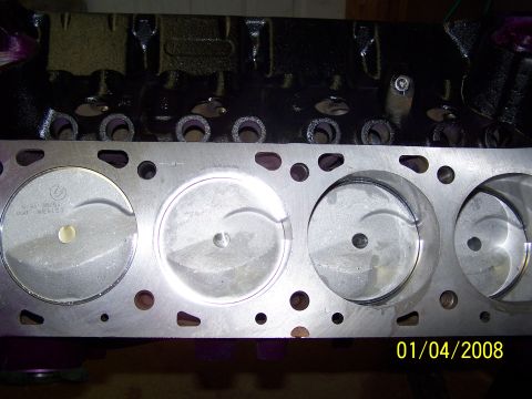 1995 Ford Bronco - Close-up view of an engine block's cylinder head mating surface and pistons.