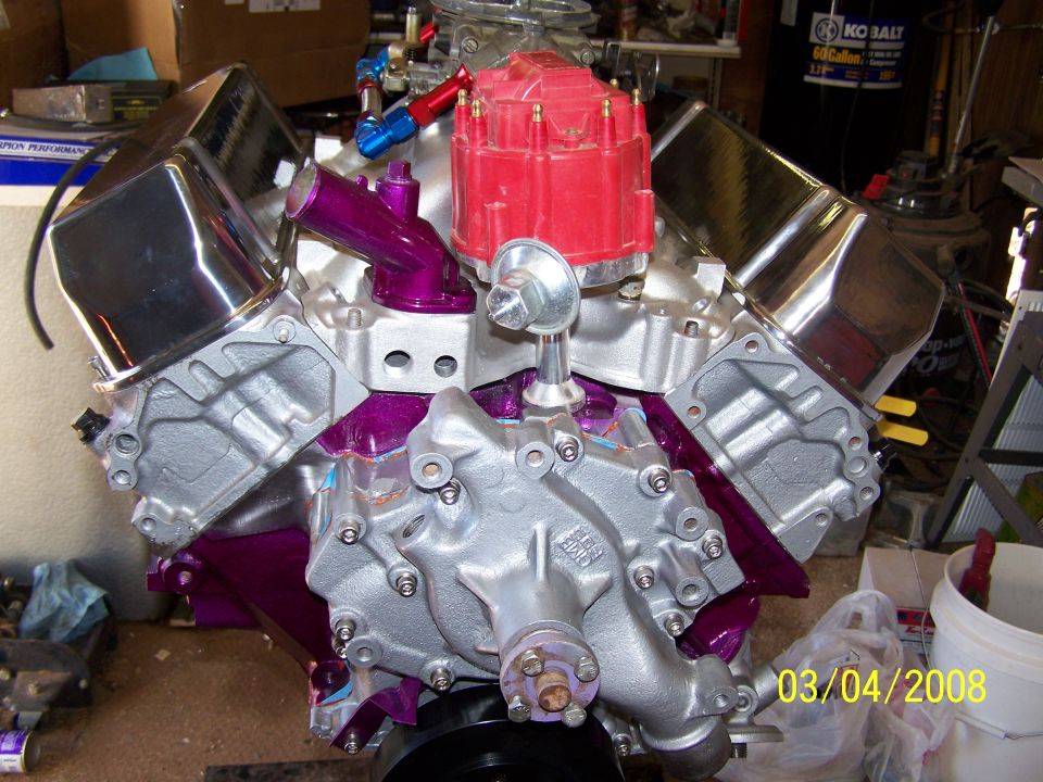 V8 engine block with chrome valve covers, red distributor cap, and purple intake manifold components