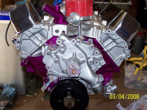 1995 Ford Bronco - A V8 engine with custom purple paint and chrome valve covers is shown in a workshop setting.