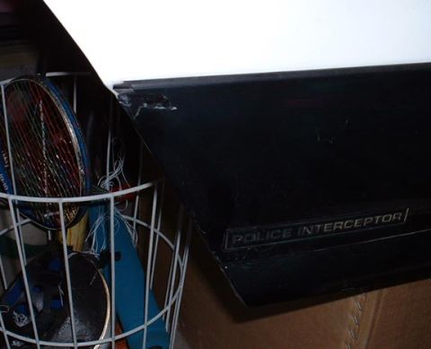 1998 Ford Crown Victoria - Detail of a 'Police Interceptor' badge on a vehicle part, beside a basket of sports equipment.