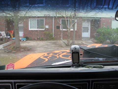 1979 Ford Bronco - View out the windshield from behind a black dash, looking over an orange hood painted with black tribal flames and fitted with a black cowl…