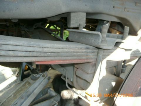 1991 Ford Bronco - Leaf spring suspension system of a vehicle, with a jack visible below.