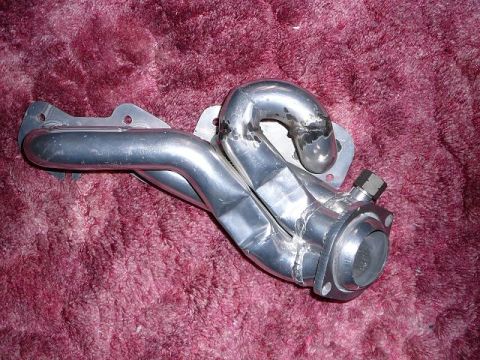 1997 Mercury Grand Marquis - A custom aluminum exhaust manifold is shown resting on a textured burgundy surface. The manifold features multiple pipes welded together an…