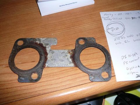 1997 Mercury Grand Marquis - Two engine gaskets are laid out on a wooden table next to some papers.