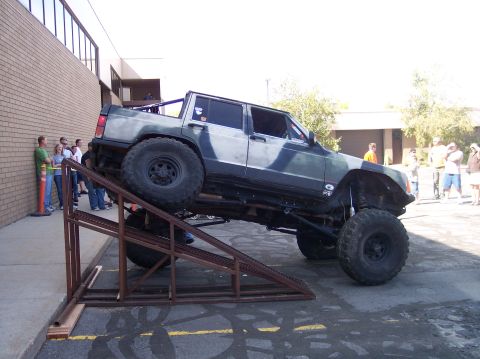 1995 Ford Bronco - A white 1995 Ford Bronco is shown tilted on its side, with its front end leaning against a brick building.