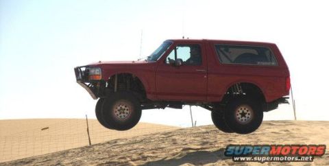1984 Ford Bronco - A red SUV is captured in a side profile view, isolated against an indistinct backdrop.