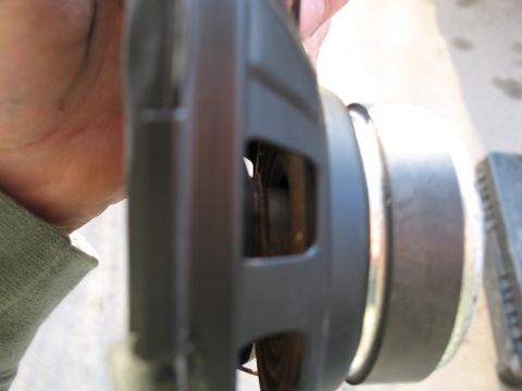 1995 Ford Bronco - A hand holds a car speaker, showing its side profile and internal components.