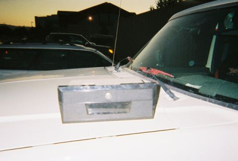1991 Ford Bronco - A gray storage box and antenna are mounted on the hood of a white vehicle.