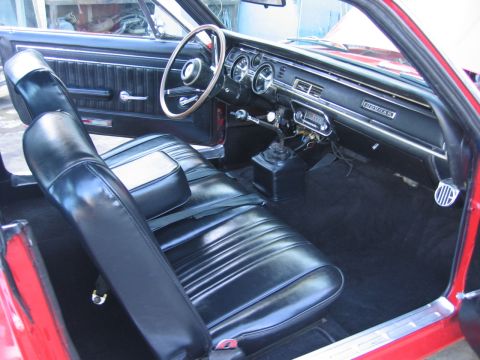 1973 Mercury Cougar - The interior of a red car shows black vinyl seats and a dashboard with 'COUGAR' badging, suggesting a model from the early 1970s.