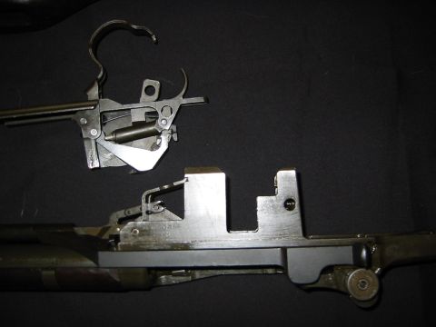 1996 Ford Bronco - Disassembled gun parts, including the receiver and trigger assembly, are laid out against a dark surface.