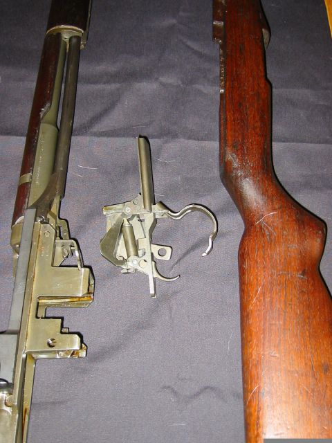1996 Ford Bronco - A disassembled firearm trigger group and wooden stock are laid out on a dark surface.